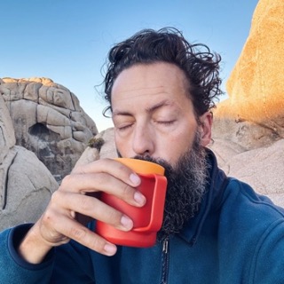 Kristian Kruse drinking coffee outdoors among desert rock formations.